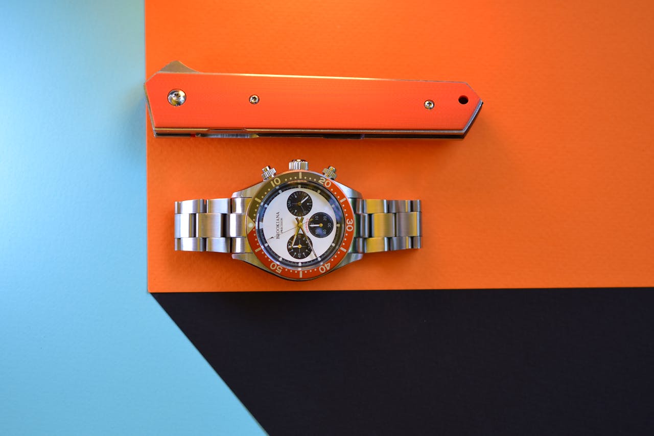 A sleek watch and knife on a colorful geometric background representing modern style and precision.