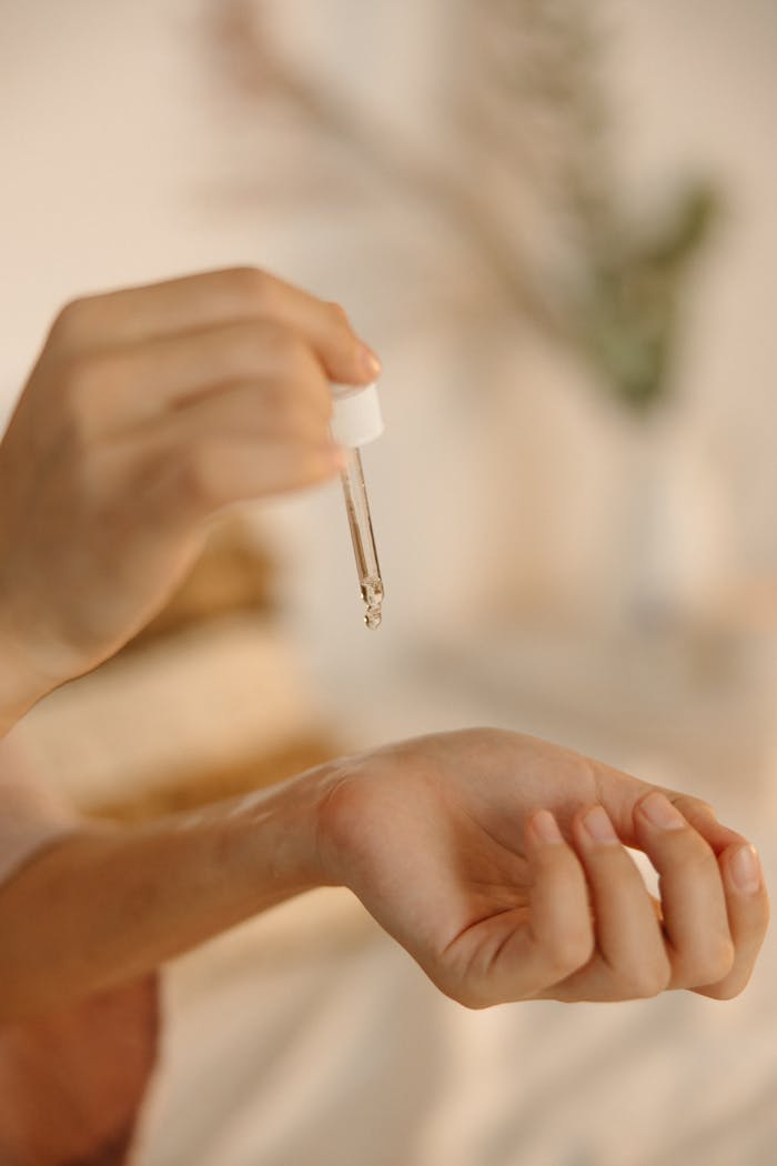 Close-up image of a hand using a dropper to apply skincare serum.